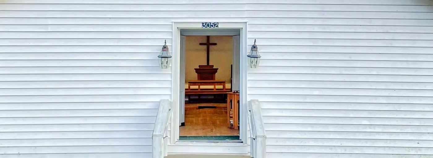 The white Communion Fellowship church building on its hillside in Mendota